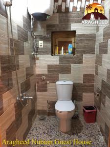 a bathroom with a toilet and a tiled wall at Nubian Kingdom Aragheed House in Aswan