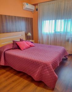 1 dormitorio con 1 cama grande con manta rosa en Apartamento El Colón en Buenos Aires