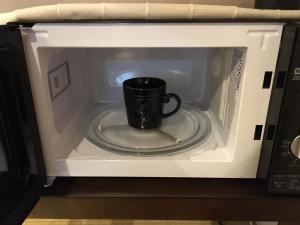 a coffee mug is inside of a microwave at Guesthouse Arakura ,Private 2F Stay ,Walk to Chureito Pagoda in Fujiyoshida