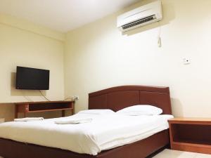 a bedroom with a bed and a tv on the wall at HK Inn Hua Kiew Inn in Miri