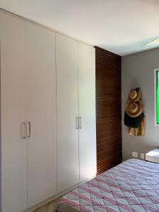 a bedroom with white cabinets and a bed with a hat at Apartamento lazer na rua da praia in Riviera de São Lourenço