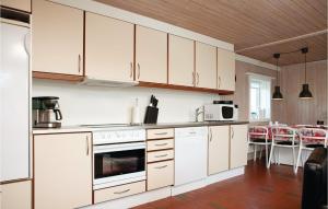 uma cozinha com armários brancos e uma mesa e cadeiras em 2 Bedroom Beautiful Home In Pandrup em Rødhus