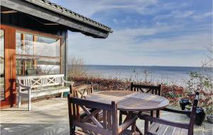 a wooden table and chairs on a patio with the ocean at Three-Bedroom Holiday Home Bjert With Sea View 08 in Sønder Bjert