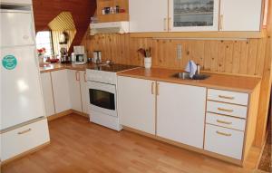 a kitchen with white cabinets and a sink and a refrigerator at Westside in Søndervig