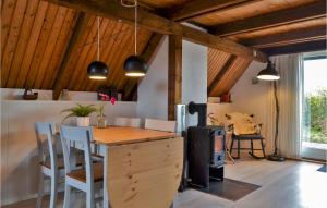 Bjerregårdにある3 Bedroom Amazing Home In Hvide Sandeの木製の天井、テーブルと椅子付きのキッチン