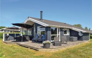 una casa con terraza con sillas y sombrillas en Stunning Home In Rudkbing With Sauna, en Spodsbjerg