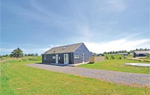 a black house with a gray roof on a grass field at Awesome Home In Brovst With 3 Bedrooms, Sauna And Wifi in Brovst