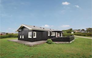 a black house with a porch and a grass field at Three-Bedroom Holiday Home In Vinderup in Vinderup