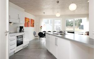 a kitchen with white cabinets and a dining room at Nice Apartment In Lkken With 4 Bedrooms, Sauna And Wifi in Løkken