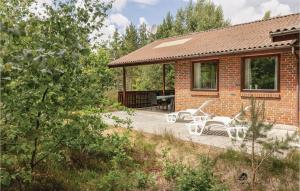 a brick house with a patio and white chairs at Stunning Home In Nex With 3 Bedrooms, Sauna And Wifi in Balke