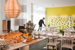un ristorante con tavoli e un uomo sullo sfondo di Novotel Lausanne Bussigny a Losanna