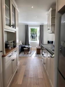 cocina con armarios blancos y suelo de madera en Garden Cottage - Leafy Constantia Guest House, en Ciudad del Cabo