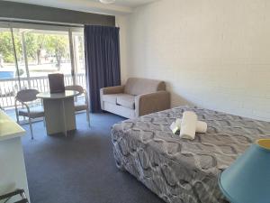 ein Hotelzimmer mit einem Bett und einem Stuhl in der Unterkunft Dalby Manor Motor Inn in Dalby