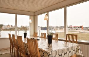 a dining room with a table and chairs and windows at Nice Home In Ringkbing With 4 Bedrooms in Søndervig