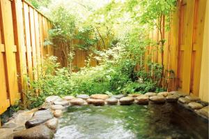 einen Garten mit einem Teich in einem Holzzaun in der Unterkunft Anise Garden in Hakuba