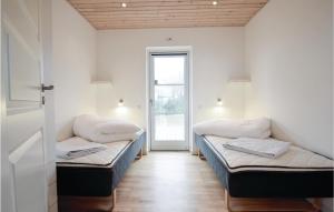 two beds sitting in a room with a door at Awesome Home In Rudkbing With Sauna in Spodsbjerg