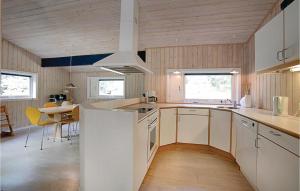 Vester SømarkenにあるNice Home In Nex With 4 Bedrooms, Sauna And Wifiの白いキャビネットとテーブル付きのキッチンが備わります。