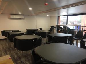 ein leeres Zimmer mit Tischen und Stühlen und einem Fenster in der Unterkunft Rahman Hostel in Manchester