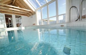 a large swimming pool with blue water in a building at Lovely Home In Hvide Sande With Kitchen in Havrvig