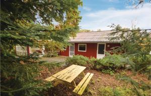 a wooden picnic table in front of a red house at Gorgeous Home In Spttrup With Kitchen in Spottrup