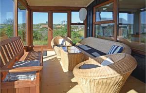 trzy wiklinowe krzesła i stoły na ganku z oknami w obiekcie Amazing Home In Hvide Sande With Kitchen w mieście Hvide Sande
