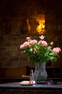un jarrón azul y blanco con flores rosas sobre una mesa en Riad Jade Mogador, en Essaouira