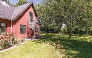 a red house with a tree and a yard at 0-Bedroom Apartment In Nexo in Neksø