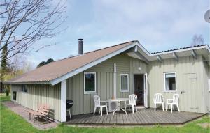 a green house with chairs and a table on a deck at Amazing Home In Kirke Hyllinge With 3 Bedrooms, Sauna And Wifi in Kirke-Hyllinge