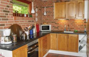 a kitchen with wooden cabinets and a brick wall at Beautiful Home In Spttrup With Wifi in Lihme