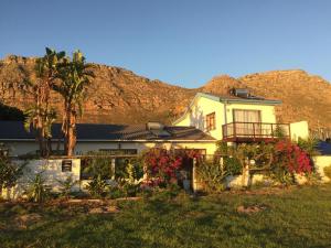 a white house with a mountain in the background at The Speckled Egg, 4 Promenade Rd, Lakeside, Cape Town in Cape Town