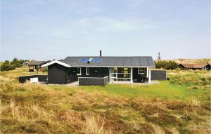 Ein schwarzes Haus auf einem Hügel mit einem Feld in der Unterkunft Awesome Home In Fan With Kitchen in Sønderho