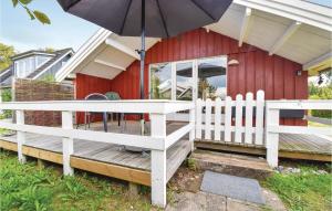 una casa roja con una valla blanca y una sombrilla en Awesome Home In Brenderup Fyn With House Sea View en Vedelshave