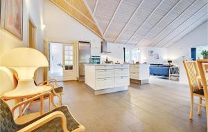 ブラーバンドにある5 Bedroom Gorgeous Home In Blvandの白いキャビネット、テーブルと椅子付きのキッチンが備わります。