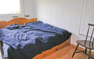 a bed with a blue blanket and a chair in a room at Nice Home In Frstrup With Kitchen in Lild Strand