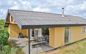 a small yellow house with a wooden deck at Nice Home In Frstrup With Kitchen in Lild Strand