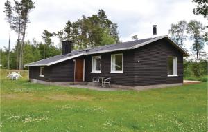 ein schwarzes Haus auf einem Feld mit einem Rasenplatz in der Unterkunft Amazing Home In Hirtshals With Wifi in Hirtshals
