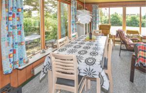 a dining room with a table and chairs and windows at Awesome Home In Fars With 3 Bedrooms in Ertebølle