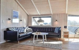 a living room with a black leather couch and a table at Holiday Home Bjerregårdsvej Denm in Bjerregård