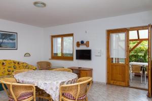 comedor con mesa, sillas y TV en Familia Apartment 100/3, en Balatonmáriafürdő