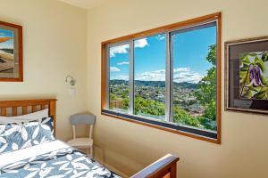 a bedroom with a bed and two windows with a view at The Nelson's Lookout in Nelson