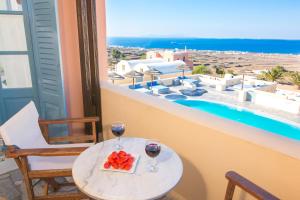 a table with two glasses of wine and a plate of fruit at Anemoessa Villa in Oia