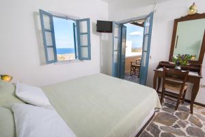 a bedroom with a bed and a desk and windows at Anemoessa Villa in Oia +37 photos