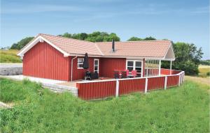 una casa roja con terraza en un campo en Pet Friendly Home In Augustenborg With Kitchen en Asserballeskov