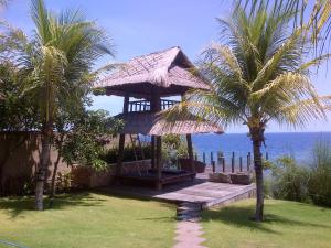 a gazebo on the beach with a palm tree at Villa Bukit Segara in Amed