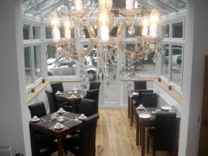 a dining room with tables and a chandelier at Devonshire Hotel in Hornchurch