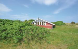 a red house on a hill in a field at Amazing Home In Frstrup With 3 Bedrooms And Sauna in Lild Strand