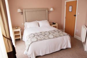 1 dormitorio con 1 cama grande con sábanas y almohadas blancas en Devonshire Hotel, en Hornchurch