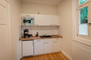 a kitchen with white cabinets and a microwave at Ferienwohnungen an der Salvatorkirche - zentrales Apartmenthaus mit Terrasse in Coburg