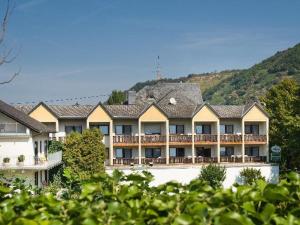 ein großes Resortgebäude mit einem Berg im Hintergrund in der Unterkunft Hotel Krone Riesling in Trittenheim