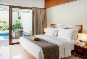 a hotel room with a bed and a balcony at The Magani Hotel and Spa in Legian
